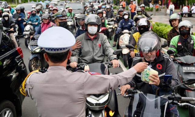 Fastenbrechen auf der Straße. Polizisten in der indonesischen Metropole Jakarta verteilen Essen und Getränke.