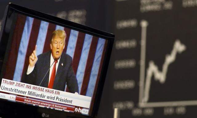 A TV screen showing U.S. President-elect Trump is pictured in front of the German share price index DAX board in Frankfurt