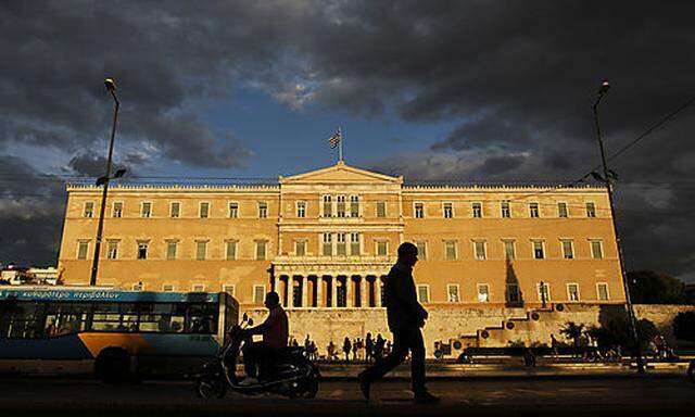 A man walks as vehicles drive in front of the  Greek Parliament, on Wednesday, Sept. 21, 2011. Greece