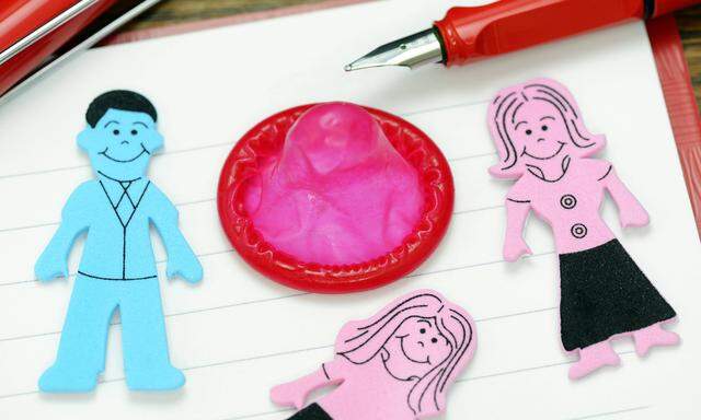 Figuren von Mann Frau und Kind und Kondom in einem Heft Symbolfoto Sexualkundeunterricht