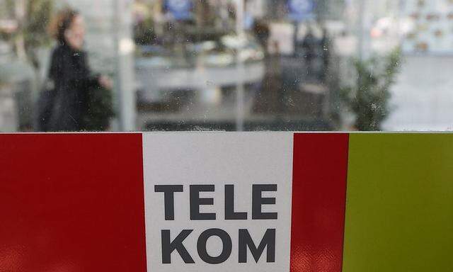 A woman makes a phone call behind a sign of Telekom Austria in Vienna