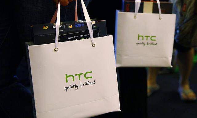 Customers hold bags containing their HTC One mobile phone purchases during the first day of public sales in Jakarta