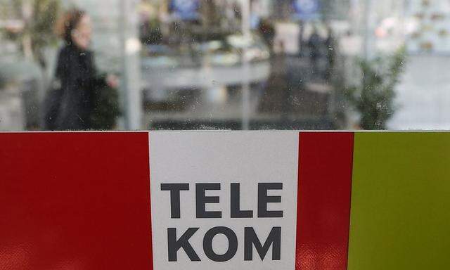 A woman makes a phone call behind a sign of Telekom Austria in Vienna