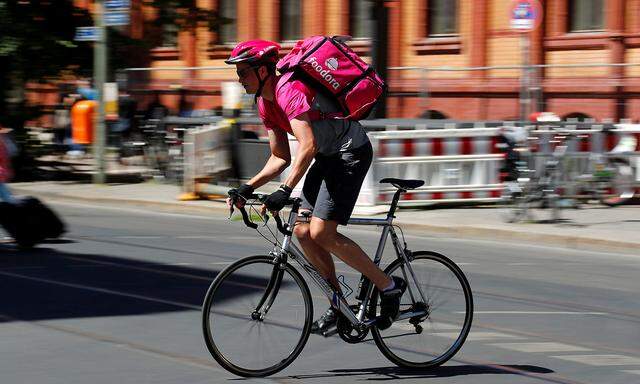 A Foodora delivery cyclist poses on a street in Berlin