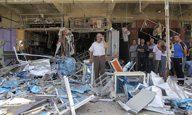 Residents stand among debris at one of the scenes of car bomb attacks that struck Baghdad