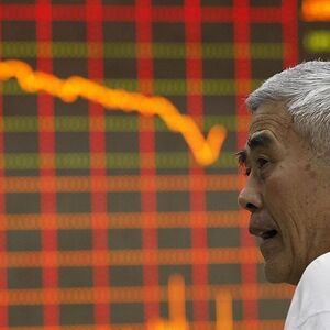 An investor stands in front of an electronic board showing stock information at a brokerage house in Huaibei