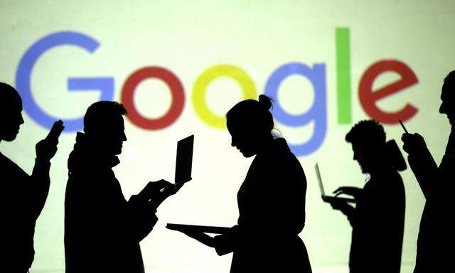 FILE PHOTO: Silhouettes of laptop and mobile device users are seen next to a screen projection of Google logo in this picture illustration