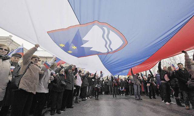 People hold up a Slovenian flag during a pro-government rally in Ljubljana