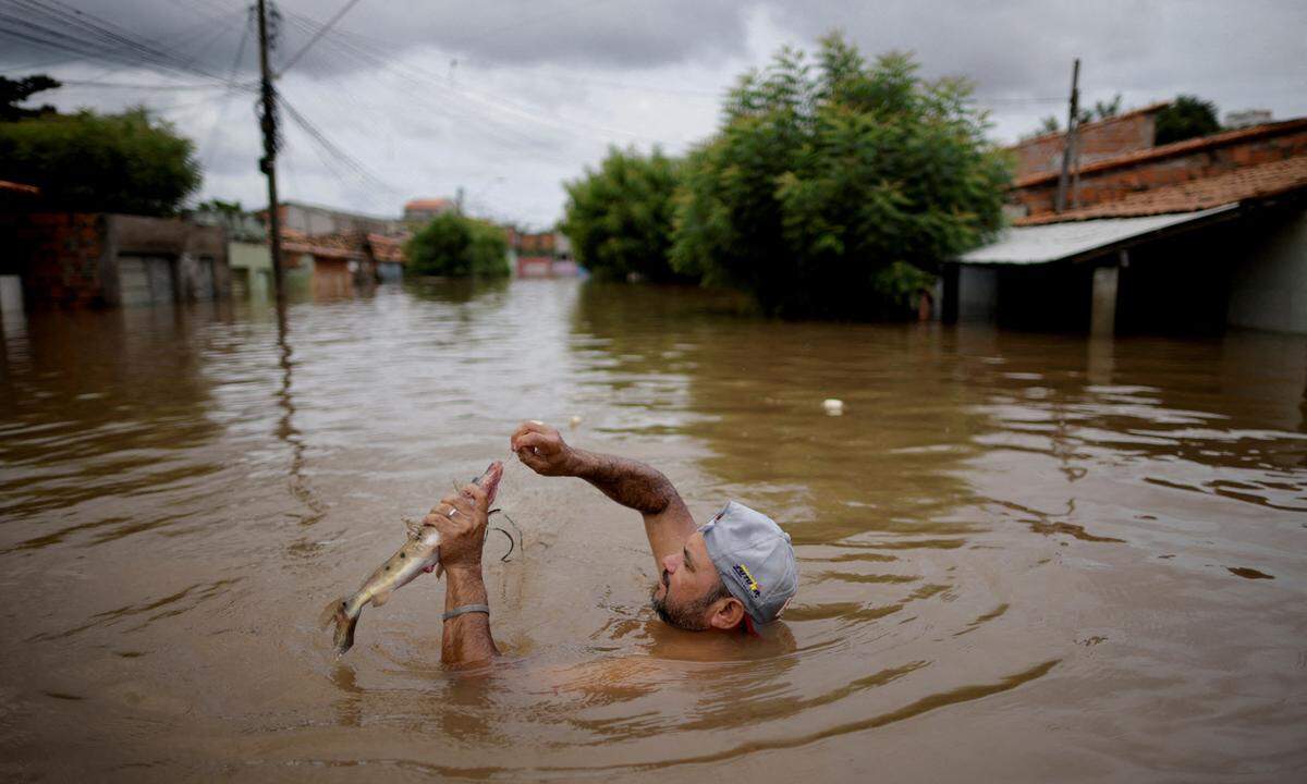 6. Jänner. Ein Mann fängt einen Fisch in einer Straße, die während Überschwemmungen durch starken Regen in Imperatriz, Bundesstaat Maranhao, Brasilien, überflutet wurde.