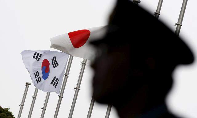 FILE PHOTO: Police officer stands guard near Japan and South Korea national flags at hotel, where South Korean embassy in Japan is holding the reception to mark the 50th anniversary of normalisation of ties between Seoul and Tokyo, in Tokyo