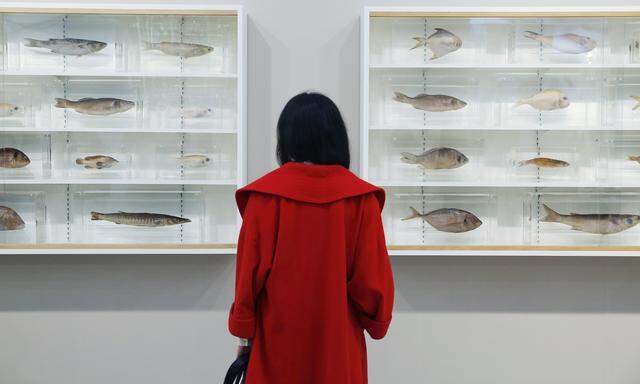 A visitor poses with artist Damien Hirst´s artwork ´Because I Can´t Have You I Want You´ at the Frieze Art Fair in London