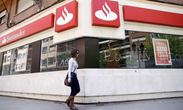 A woman walks past the vandalized windows of a Banco Santander branch in Valencia
