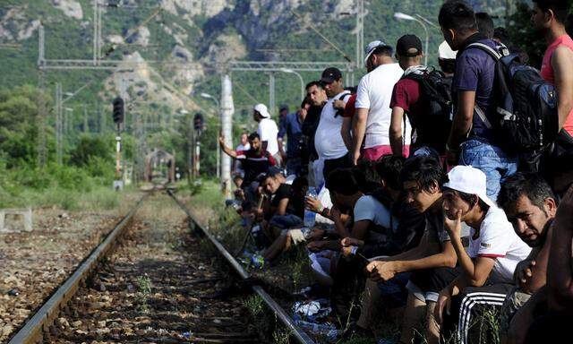 Migrants wait beside railway tracks for trains at Demir Kapia train station in Macedonia, near the border with Greece