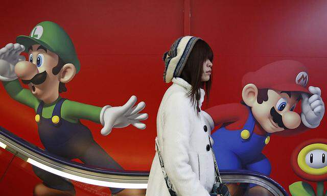 A shopper rides an escalator past Nintendo ads at an electronics retail store in Tokyo