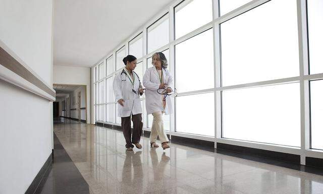 Two doctors in discussion walking down corridor PUBLICATIONxNOTxINxIND