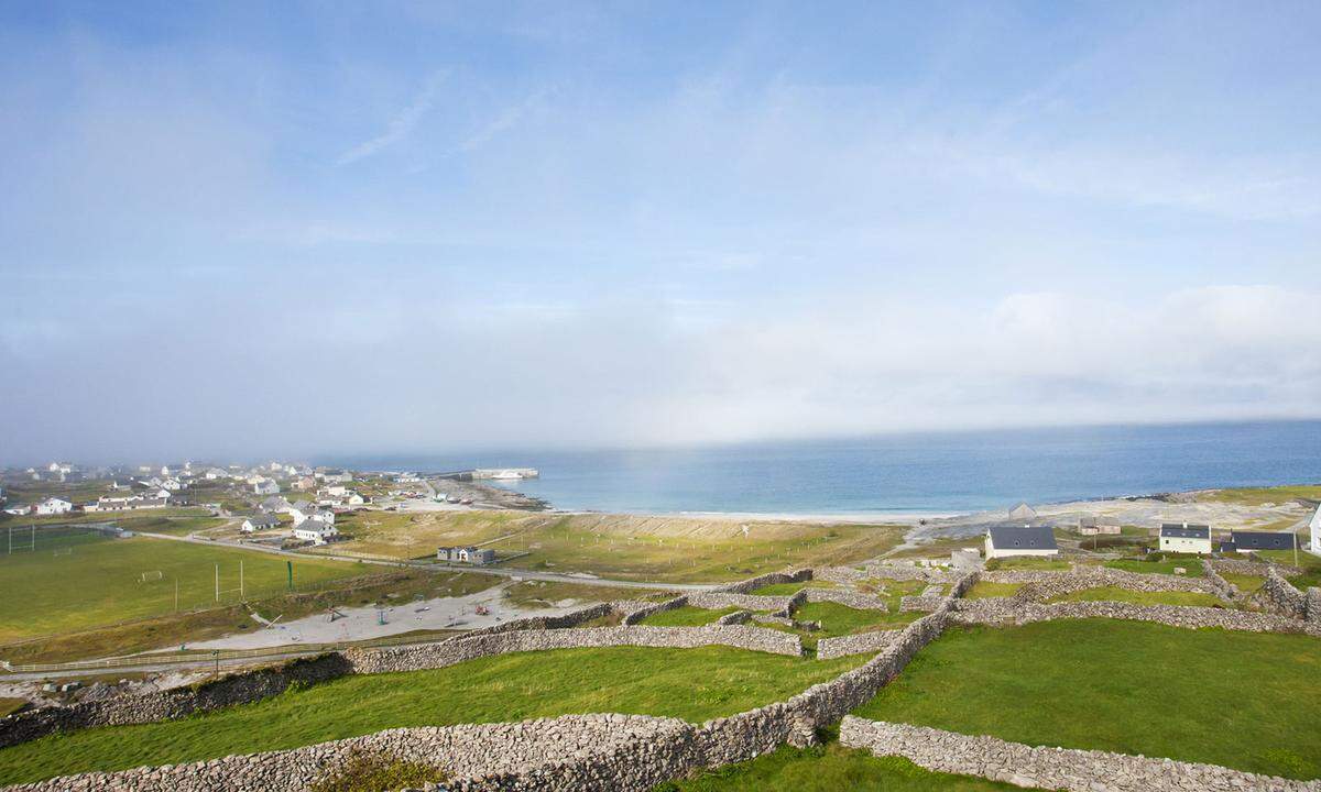 Der 49-Jährige stammt aus Dublin und arbeitet auf der Fähre: „Diese Insel ist für mich die schönste“ – und zeigt auf den weiten Sandstrand. Er gehört zur ersten der drei Inseln. „Inis Oirr, man nennt sie auch die goldene, weil der Sand in der Sonne leuchtet.“ (im Bild) Dort fänden sich Überreste aus der Bronzezeit, dem frühen Christentum, dem Mittelalter und sogar von Napoleon, erzählt er. Während die Fähre an der mit 150 Bewohnern kleinsten der drei Inseln kurz anlegt, entdeckt Tim einen Delfin im Hafenbecken, ganz ohne teure Delfin-Watching-Tour.  