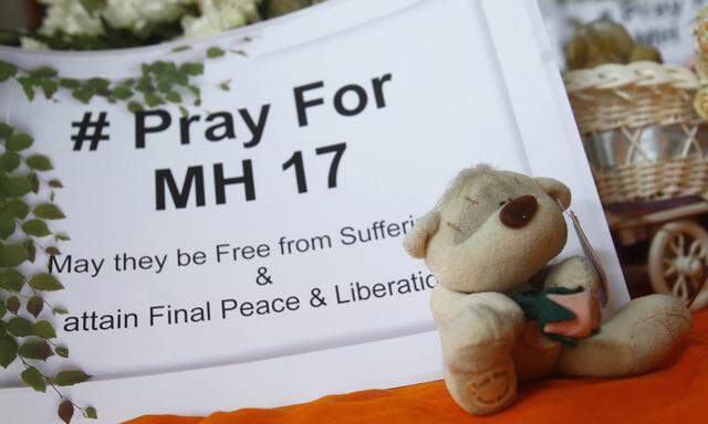 A toy bear rests near a sign during a special vigil for victims of the downed Malaysia Airlines Flight MH17, inside a temple in Kuala Lumpur