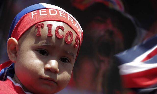 A Costa Rican child with the word 'ticos' on his forehead watches a large screen broadcasting the 2014 World Cup soccer match between Costa Rica and Italy, at the Democracia square in San Jose
