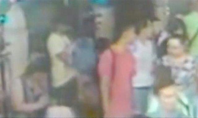 Ein Videostandbild zweier weiterer Verdächtiger (rotes und weißes T-Shirt) am Tatort in Bangkok.