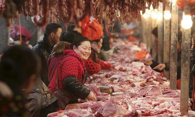 A meat vendor smiles as she talks to customers at a market in Huaibei