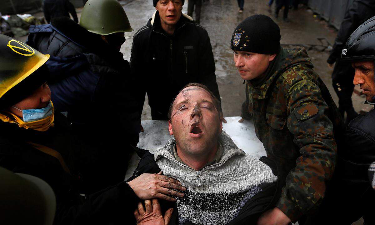 20. Februar 2014. Ein Verwundeter ringt um Atem während er von Hilfskräften auf dem Kiewer Unabhängigkeitsplatz versorgt wird. Präsident Viktor Janukowitsch floh schließlich ins Ausland.