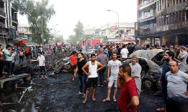 People gather at the site of a suicide car bomb in the Karrada shopping area, in Baghdad, Iraq 