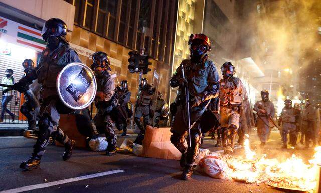 Polizisten durchbrechen in Hongkong eine brennende Barrikade.