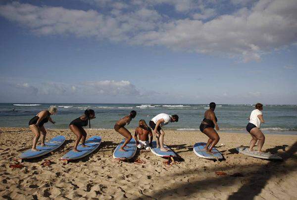 Touristen beim Trockentraining bevor sie in Waikiki die Wellen testen.