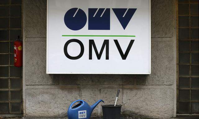 Watering cans are palced in front of the logo of Austrian energy group OMV at a gas station in Vienna