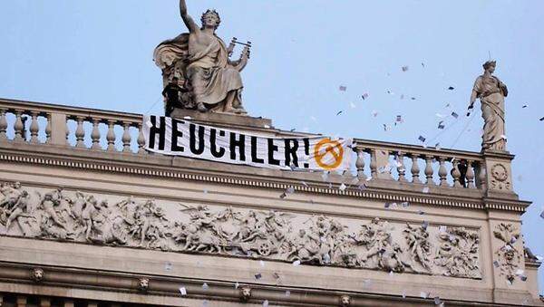 Zwei Wochen später wird erneut gegen das Stück „Die Schutzbefohlenen“ protestiert, diesmal aufgrund einer Aufführung im Burgtheater (im Bild eine Aufnahme der Identitären). Fünf Identitäre enthüllen am Dach des Wiener Burgtheaters ein Transparent und werfen Flugblätter ab.