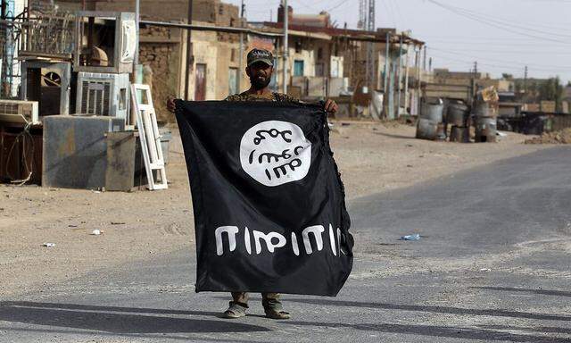 In irakischer Kämpfer zeigt in al-Qaim eine verkehrt gehaltene Flagge des IS in die Kamera, nachdem die IS-Kämpfer aus der Stadt vertrieben wurden.