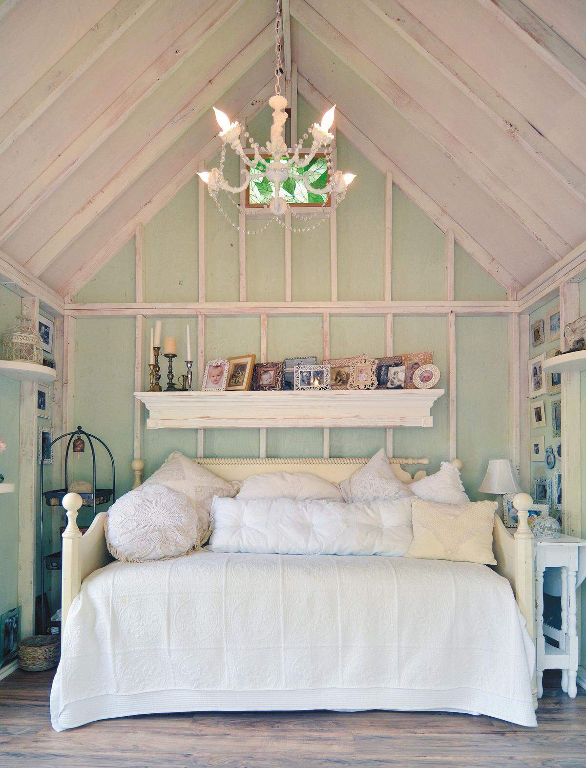 . . . Ein komfortables Tagesbett umgeben von Regalen sowie bekrönt von einem Kaminsims, der als Regalbrett dient und mit gerahmten Fotos bestückt ist.