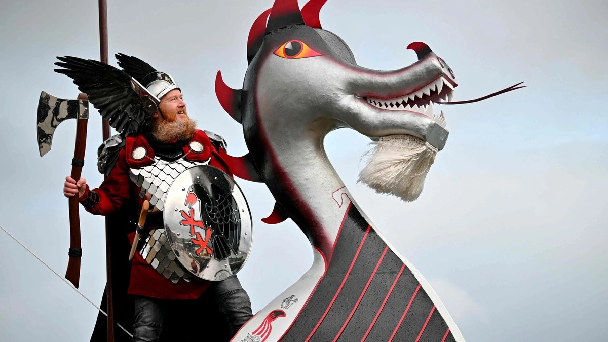 TOPSHOT - Lynden Nicolson (C), the ÔGuizer JarlÕ of the Up Helly AA Jarl Squad poses for a photograph after parading through the streets in Lerwick, Shetland Islands on January 27, 2026 before the Up Helly Aa festival later in the day. Up Helly Aa celebrates the influence of the Scandinavian Vikings in the Shetland Islands and culminates with up to 1,000 'guizers' (men in costume) throwing flaming torches into their Viking longboat and setting it alight later in the evening. (Photo by ANDY BUCHANAN / AFP)