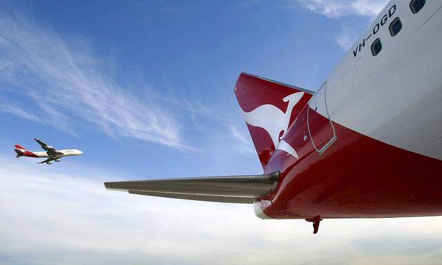 File photo of a Qantas Boeing 747 flying past a 767 airplane with a newly unveiled Qantas logo on its tail in Sydney