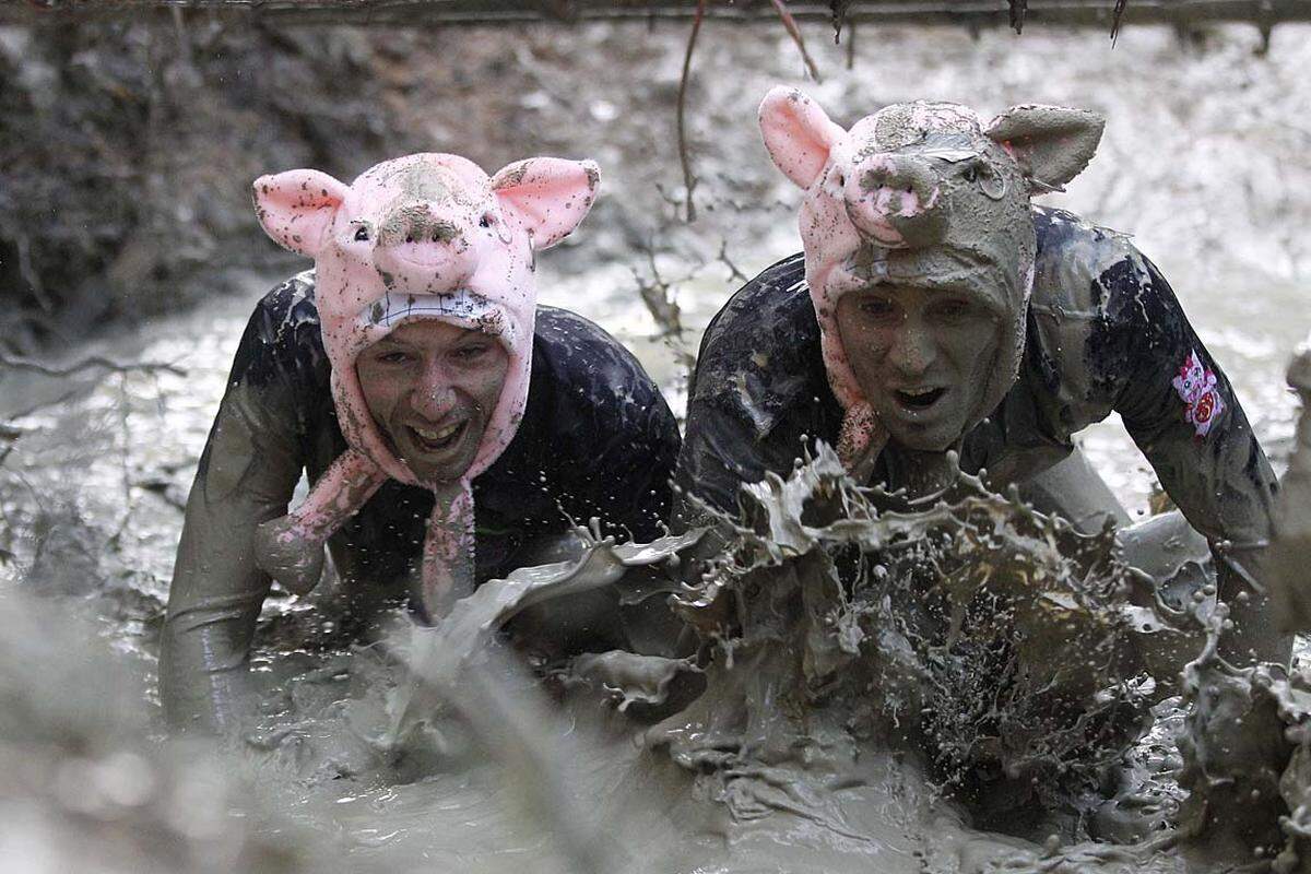 Laaben, Österreich. Beim Wildsau Dirt Run schmeißen sich zwei Teilnehmer mit Begeisterung in den Schlamm.