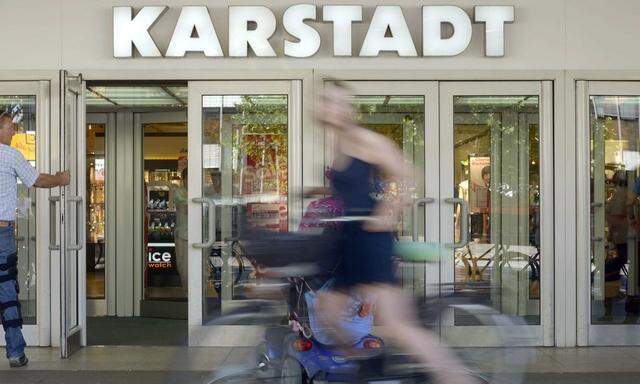 Woman on a bicycle passes an outlet of the German department store chain Karstadt in Hamburg,