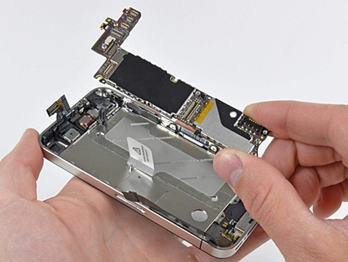 Die Haupplatine wird aus dem iPhone 4 ausgebaut. iFixit zerlegte das 32-Gigabyte-Modell, in dem laut Bericht nur 29,06 Gigabyte Speicher zur Verfügung standen.