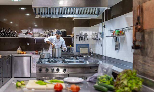 Concentrated male chef in jacket cooking meal in stainless saucepan on gas stove in restaurant kitchen MikelAllica_Profe