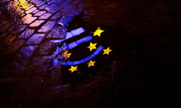 Euro sculpture is partially reflected in a puddle in front of the headquarters of the ECB headquarters in Frankfurt