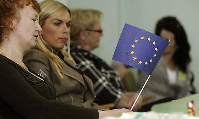 Election official plays with European Union flag as she waits for voters during European Parliament e