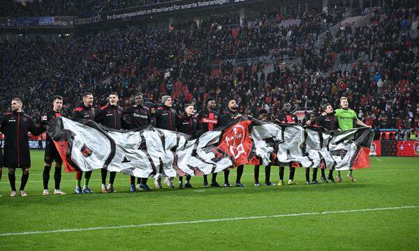 Leverkusens Spieler feiern mit den Fans. 