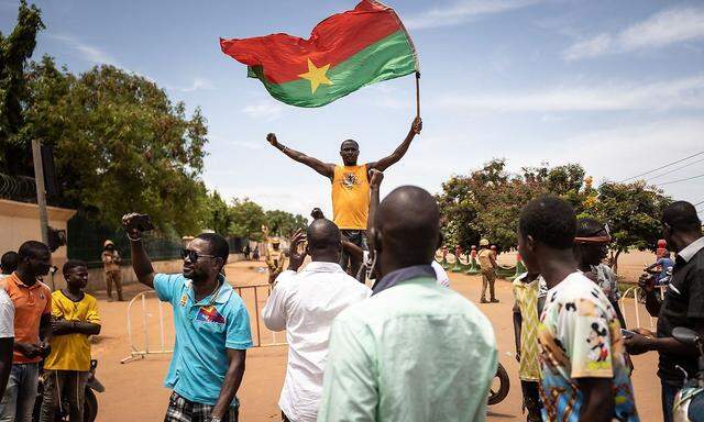 Ein Mann schwenkt eine Flagge von Burkina Faso, während andere demonstrieren und Soldaten aus Burkina Faso am 30. September in Ouagadougou im Einsatz sind.