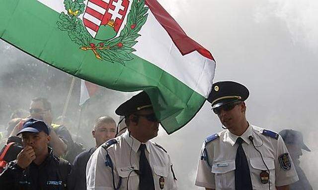 Police officers watch as firefighters take part in a  protest march against the Hungarian government