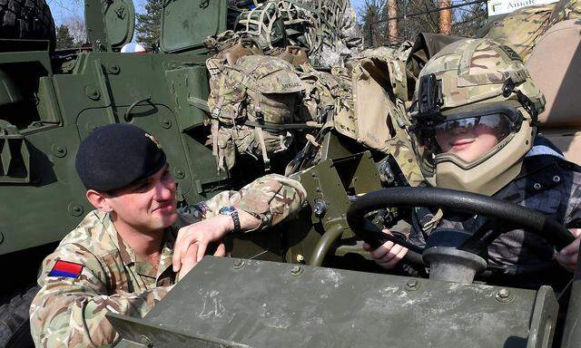 Ein britischer Soldat zeigt einem Buben in Polen Militärausrüstung.