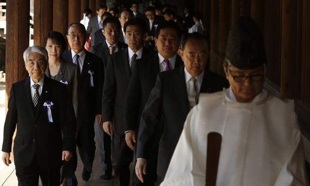 A group of lawmakers are led by a Shinto priest as they visit Yasukuni Shrine in Tokyo