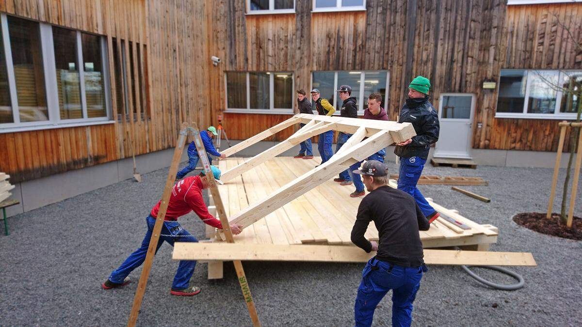 Die Montage beginnt. Die Seitenwände werden auf der Holzbodenplatte aufgerichtet.