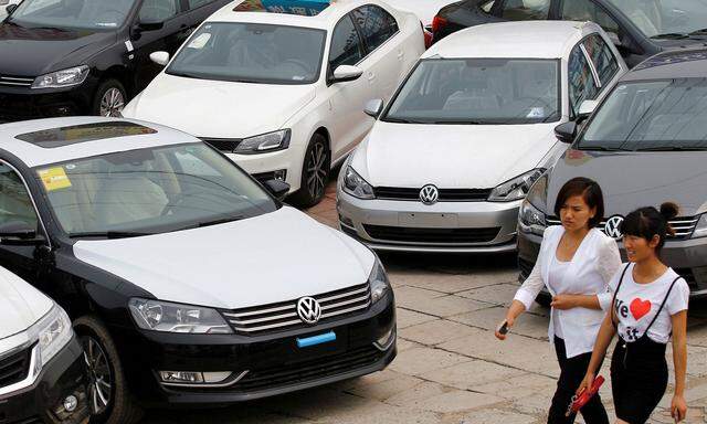 FILE PHOTO: Women walk past Volkswagen and Honda cars on display at an automobile market in Beijing