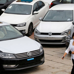 FILE PHOTO: Women walk past Volkswagen and Honda cars on display at an automobile market in Beijing