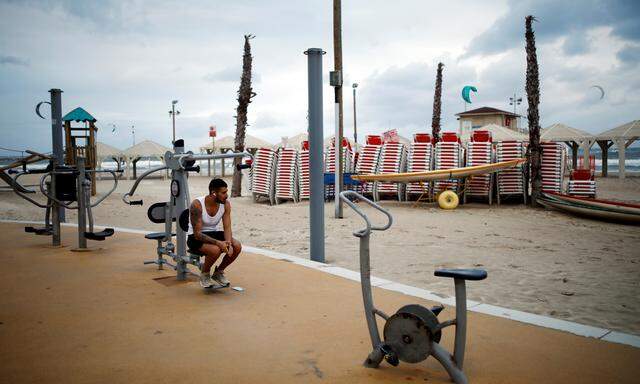 A man sits at an outdoor gym by the Mediterranean Sea in Tel Aviv