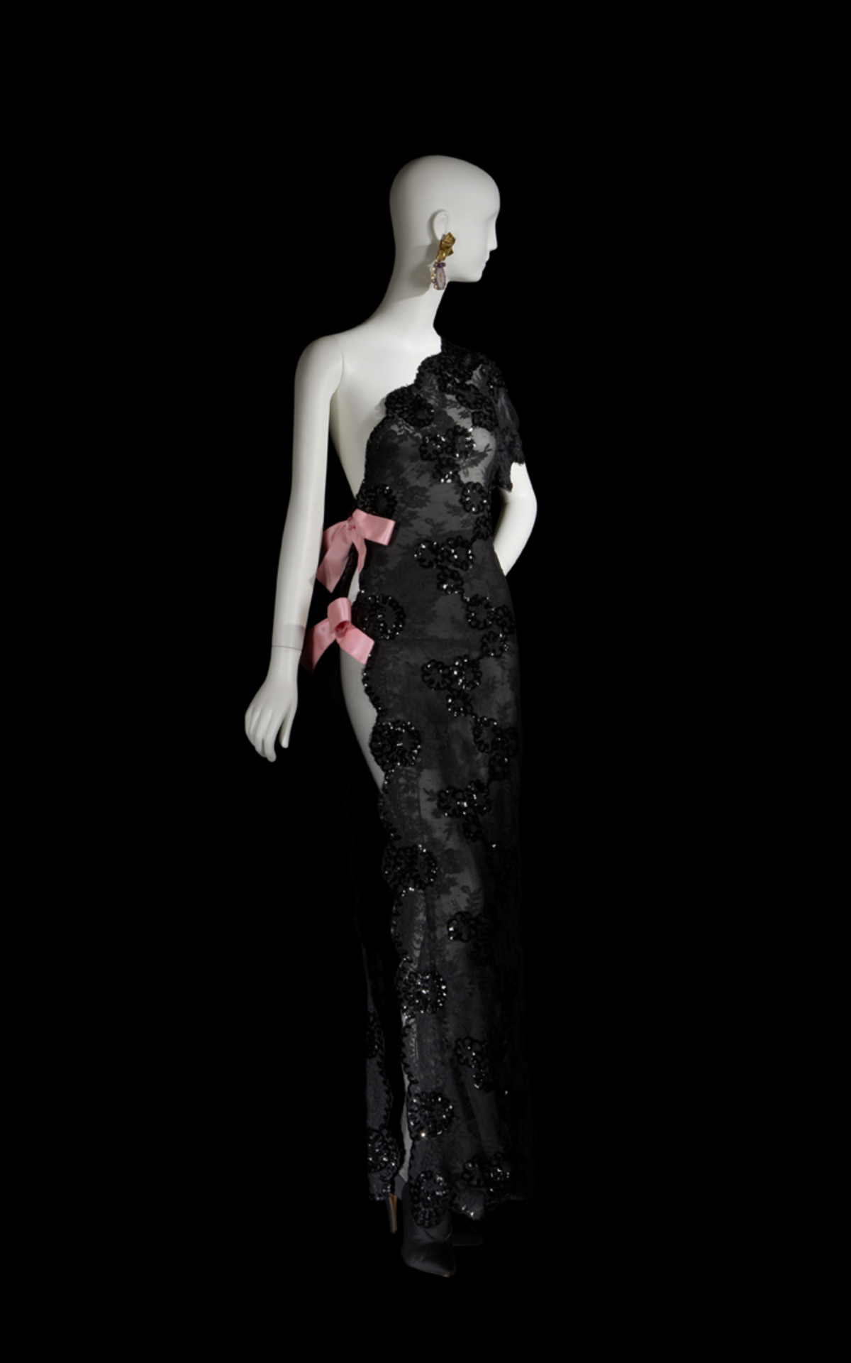 So transferierte er Smokings, Hosenanzüge, Shorts und Safari-Jacken in die Welt der Haute Couture. Langes Abendkleid aus schwarzer Pailettenspitze und pinken Satinschleifen aus der Haute Couture Kollektion 1990.